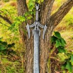 Luciender Sword of Light Replica embedded vertically in forest soil with tree trunk backdrop and fantasy ambiance