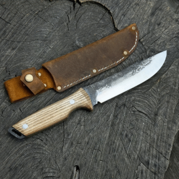 Custom hunting knife by Ashblades, showcasing a full tang blade with a rough-forged finish near the spine and a finely polished edge for precision cutting. The handle is crafted from natural wood and riveted for durability, while the brown leather sheath includes reinforced stitching and a belt loop for easy field access. Perfect for bushcraft, skinning, and outdoor adventure setups, this knife is photographed on rustic timber with bark accents for a rugged aesthetic.