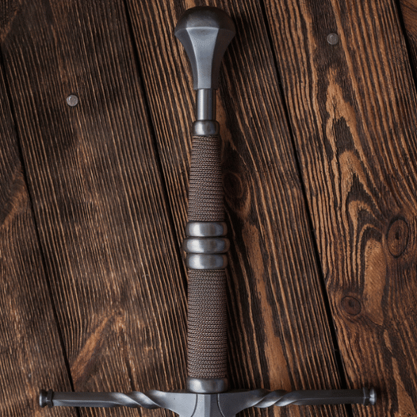 Training version of Geralt of Rivia steel sword replica with 2–2.5 mm thick edges and 50 HRC hardness, balanced closer to the hilt for safe sparring, shown in a studio setting with soft lighting to emphasize its durability and suitability for LARP and practice