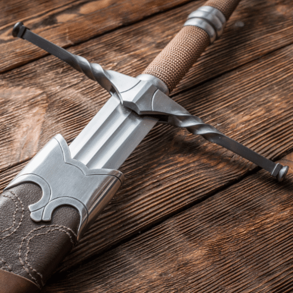 High-resolution image of Geralt of Rivia steel sword replica, handcrafted from spring steel with carbon steel crossguard and surgical steel pommel, wrapped in natural leather grip, displayed diagonally against a dark fantasy-themed background for collectors and cosplay fans.